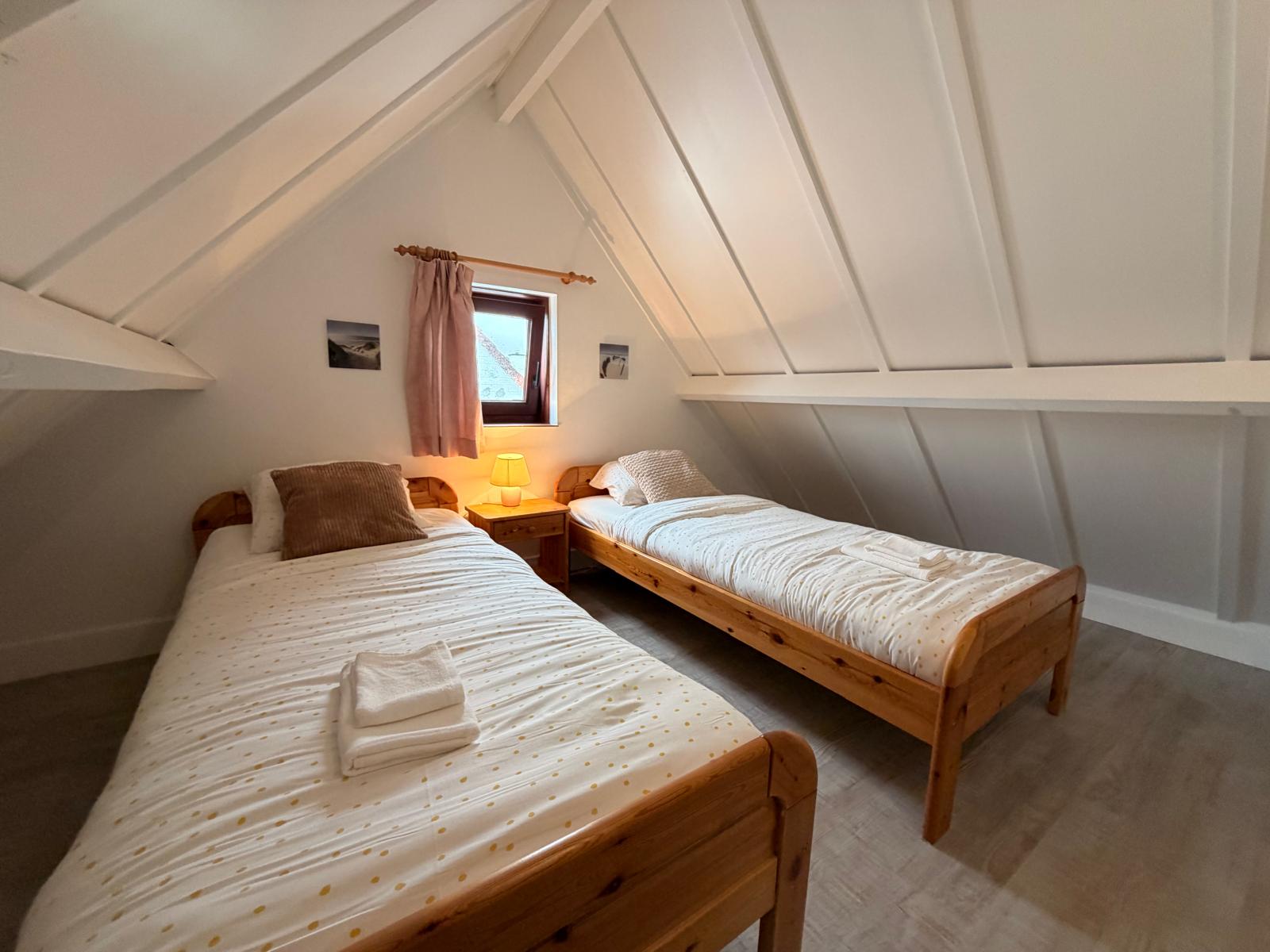 Upstairs bedroom with two beds beneath the sloping roof